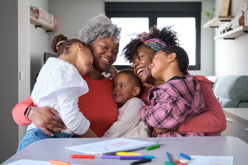 African horizontal extended family hugging and laughing at home.