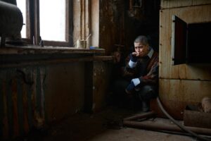 Needy homeless woman smoking cigarette sitting in corner of room