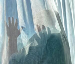 Looking out a window behind a curtain late afternoon. Light and Shadow