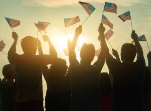 Silhouettes of people holding the flag of USA.