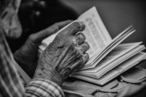 Elderly man's hand turning the page of a book. Black and white photography