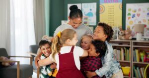 Happy woman, kids and hug teacher at school for learning, education or development in class togethe
