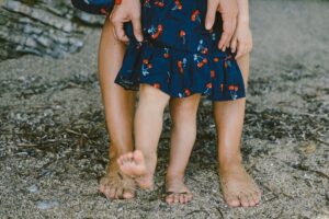 Mother and kid feet walking on a sand beach