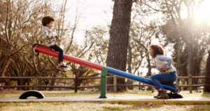 Park, mother and child with seesaw, playground and game with family balance and holiday with parent